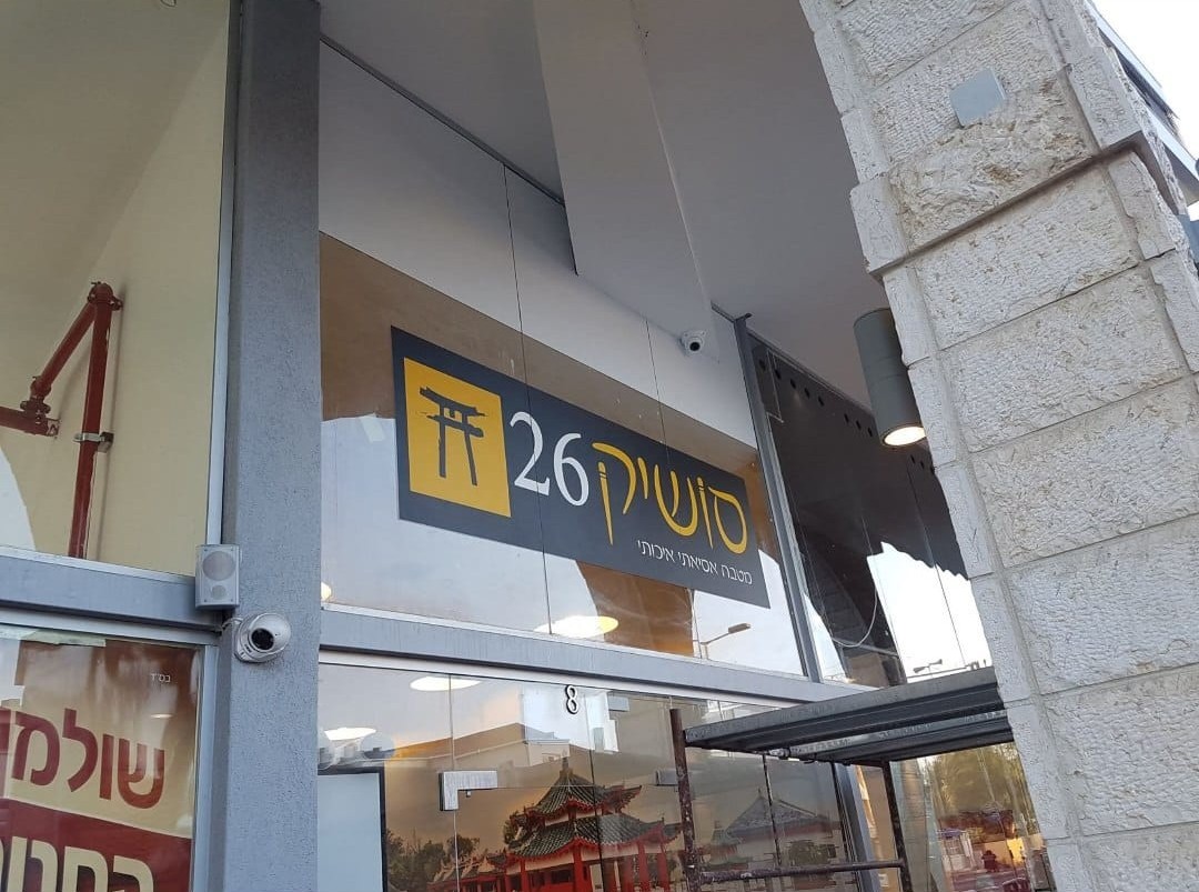 An exterior restaurant sign above the entrance beneath a covered walkway.